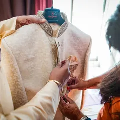 The details matter. This shot shows the groom's family helping him with the final touches on his wedding jacket, a moment of care and connection.