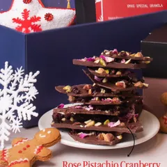 Our Rose Pistachio Cranberry & Chocolate Barks are a holiday favorite. Stacked beautifully on a plate, this image shows the rich texture and colorful ingredients that make this treat both delicious and visually appealing for any Christmas gift.