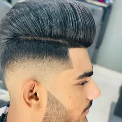 A perfect example of a high-volume pompadour with a skin fade that blends seamlessly into the beard. Every line is clean, sharp, and intentional, creating a powerful, modern look.