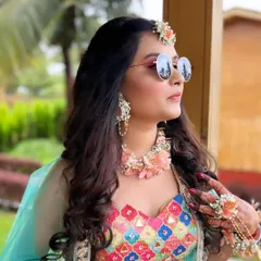 A fun, candid shot of the Haldi bride. Her colorful makeup, floral jewellery, and cool sunglasses perfectly capture the happy and relaxed vibe of the ceremony.
