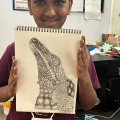 A student proudly displays his incredibly detailed drawing of a crocodile's head, a fantastic example of advanced texture work.