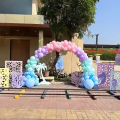 The entrance to this pre-wedding pool party featured a beautiful pastel balloon arch complemented by custom-cut panels and props like a palm tree cutout, setting a fun, beachy theme for the event.
