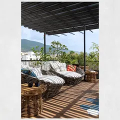 The terrace lounge at Kamala Residence was designed as a serene retreat from the city. A metal pergola frames the view of the Tirupati hills and mitigates sunlight, while cane furniture enhances the tropical theme.