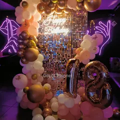 An 18th birthday deserves all the sparkle. This setup features a stunning rose gold sequin backdrop, a custom 'Happy Birthday' neon sign, and a beautiful balloon arch. The marquee numbers for '18' make it the perfect spot for celebrating this major milestone.