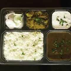 A closer look at one of our packed thalis. You can see the separate compartments for each item, which keeps the food fresh and prevents mixing. This meal includes a dry sabzi, dal, rice, salad, and boondi raita.