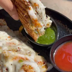 A cheesy bite of my grilled sandwich, dipped in spicy green chutney. The combination of melted cheese and tangy chutney is simply irresistible.