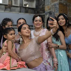The bride takes a happy selfie with her family and bridesmaids, a modern and candid moment that captures the joy of being surrounded by loved ones.