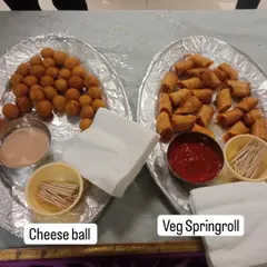 Classic party starters that everyone loves. On the left are crispy Cheese Balls with dip, and on the right are Veg Spring Rolls with ketchup.