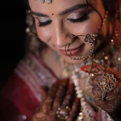 A close-up of a bride's stunning look, featuring a multi-layered kundan necklace, maang tikka, and nath. All this beautiful jewellery is available to rent along with the lehenga.