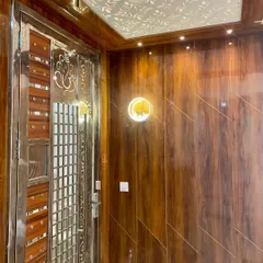 A beautiful main door entrance with full wood-panelled walls and a CNC-cut ceiling panel. The stainless steel security door adds a layer of safety.