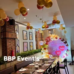 A full view of the restaurant decorated for the ring ceremony, showing the main backdrop, guest dining table, and matching balloons on the ceiling.