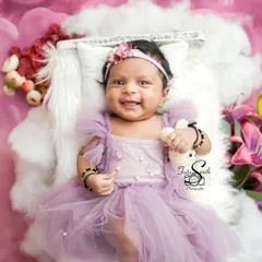 A huge, happy smile from this beautiful baby girl. Dressed in a lovely purple dress, her joy is absolutely infectious. Capturing a newborn's smile is a true treasure.
