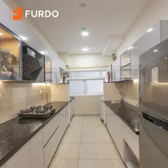 A sleek parallel kitchen with high-gloss white cabinets and black granite countertops. We maximized storage and functionality in this compact space with features like glass-front upper cabinets and under-cabinet lighting.