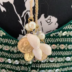 Details matter in creating a cohesive look. This is a close-up of the tassel work on a custom lehenga, featuring shells and coins, designed to match the theme of a couple's wedding outfits.
