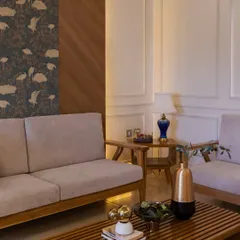 In this Jaipur residence, we used a neutral base and layered it with bold, expressive wallpapers to bring a youthful spark. This living area features a mix of wood paneling, classic molding, and a vibrant bird-patterned wallpaper.