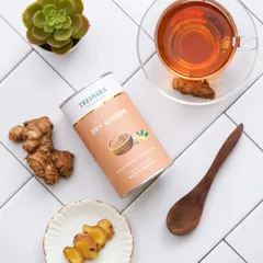 A top-down flatlay of Dry Ginger powder on a clean, tiled surface. The arrangement with fresh ginger, a cup of tea, and a succulent creates a fresh and modern aesthetic for this wellness product.
