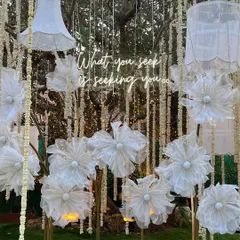 An artistic backdrop combining delicate origami flowers, traditional floral strings, and a neon quote. This installation is a beautiful blend of modern art and classic decor.