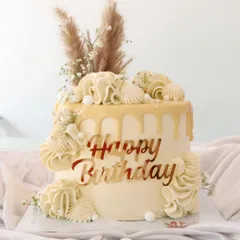 A beautiful boho-chic birthday cake. This design features a white chocolate drip, delicate piping, and is topped with dried pampas grass for a trendy, rustic vibe.