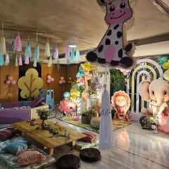 This pastel jungle setup is perfect for a "Wild One" first birthday, with low seating, a ball pit, and adorable animal cutouts like a giraffe, lion, and elephant.