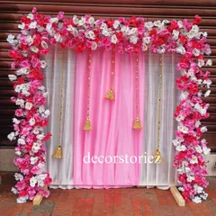 This elegant pink and white ready-to-install makhar is decorated with artificial cherry blossoms and hanging golden bells. The dual-layered curtain adds depth, making it a beautiful frame for your Ganpati idol.