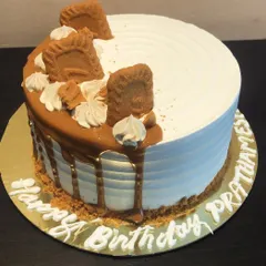 A stunning eggless Lotus Biscoff birthday cake. This design features a smooth white frosting, a Biscoff drip, and is topped with crumbled and whole Biscoff cookies.