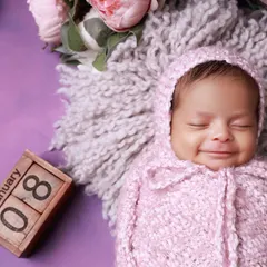 A beautiful smiling portrait of a newborn girl, part of a twin session. Capturing these fleeting smiles is a highlight of our work.