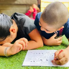 A candid moment of two kids completely absorbed in coloring a page from the Doodle Book.