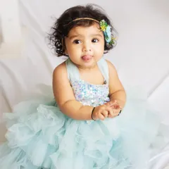 A little love in a beautiful blue tulle dress. Her curious expression and tiny tongue sticking out is an adorable, candid moment.