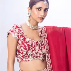 A close-up of our red bridal lehenga, showcasing the exquisite contrast embroidery on the blouse. The delicate beadwork and scalloped edges are a testament to the fine craftsmanship I select for my brides.