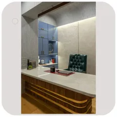 A view of the director's cabin, highlighting the custom-designed desk with its curved wooden base and marble top. The blue cabinetry in the background adds a pop of color and ample storage.