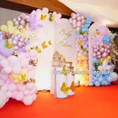A 'Baby in Bloom' baby shower with a butterfly theme. The pastel balloon arrangements in pink, purple, and blue create a soft and dreamy atmosphere.