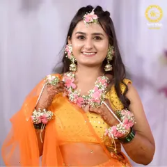 A radiant Haldi bride glowing in our custom-designed floral jewellery. This set, featuring delicate pink flowers and baby's breath, is handcrafted to perfectly complement the vibrant orange of her outfit, making her Haldi ceremony truly unforgettable.