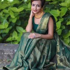 A seated portrait showcasing the beautiful drape of the green silk saree. The model's confident pose and modern hairstyle make this a perfect example of fusion fashion.
