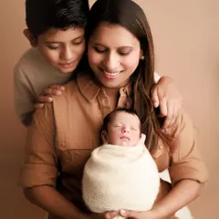 A mother holds her newborn while her older son looks on with a gentle, loving expression. Capturing the beginning of a new sibling bond is one of my greatest joys.