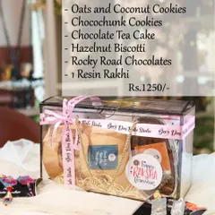 The 'Box of Love' is a transparent gift box filled with a generous assortment of baked goods. It contains Garlic and Zatar Toasties, two types of cookies, Chocolate Tea Cake, Hazelnut Biscotti, and Rocky Road Chocolates.