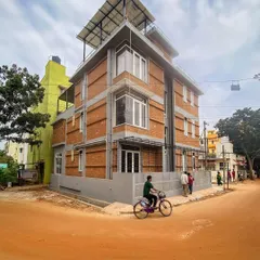 A street view of the Tripathy residence, showing its multi-level design and rooftop solar panels. The building stands as a testament to modern sustainable living within a dense urban environment.