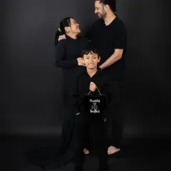 A sweet family moment where the older brother stands between his parents, all looking forward to the new arrival.