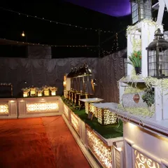 A wide shot of a buffet line setup for a formal evening event. The elegant white counters with gold accents and warm lighting create a professional and inviting atmosphere for guests.