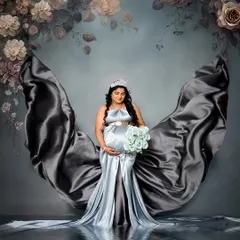 A creative portrait using a silver-blue satin gown to create beautiful, flowing shapes against a floral backdrop. The added water reflection effect gives the image a dreamy, ethereal quality.