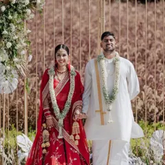 The happy couple after their day wedding ceremony. The backdrop is a modern, minimalist mandap with golden arches and delicate white floral arrangements, perfect for an elegant outdoor setting.