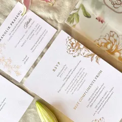 A flatlay of the modern floral suite, showing the RSVP card and the vellum sleeve with a printed floral pattern. Using vellum adds a layer of softness and luxury to the invitation set.