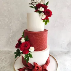 A classic combination of red and white for a wedding is always a winner. This three-tiered cake features a textured crimson tier, a big fondant bow, and is adorned with fresh red and white roses for a romantic finish.