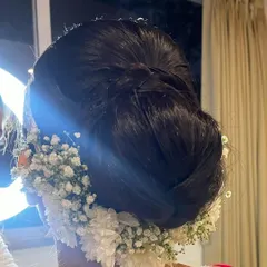 A voluminous and intricate bun decorated with a garland of fresh white flowers. This is a beautiful and traditional choice for a bride on her wedding day.