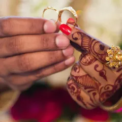 A symbolic shot of the ring exchange ceremony, focusing on the couple's hands and the wedding rings.