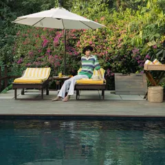 A guest relaxes on a sun lounger by the pool, embodying the serene and leisurely pace of life at Anvaya.