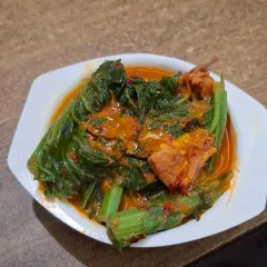 This is Gahori Manxo logot Lai Xaak, a classic Assamese dish of pork cooked with mustard leaves. The slight bitterness of the greens perfectly complements the richness of the pork.