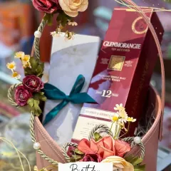 A perfect gift for a birthday party. This elegant basket hamper includes a bottle of Glenmorangie single malt scotch whisky and other treats, all beautifully decorated with flowers.