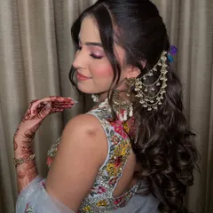 A side profile showcasing her complete Mehendi look. The combination of the floral hairstyle, colorful makeup, and stunning jewelry is just perfect.