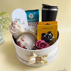 This premium Diwali hamper, presented in a round velvet box, is filled with a mix of modern tech like Realme buds, a travel mug, gourmet snacks, and a floral-scented candle.