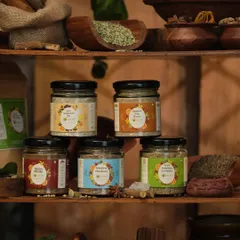 A collection of assorted spice jars neatly arranged on a rustic wooden shelf. This shot is perfect for showcasing a brand's entire product range in an authentic, kitchen-like setting.